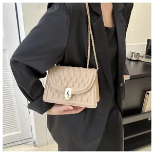 Detail of beige quilted faux leather bag with gold chain strap and metal lock closure