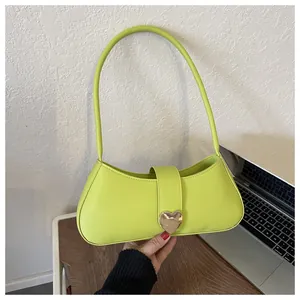 Detailed view of neon green underarm bag with gold heart-shaped buckle and smooth finish