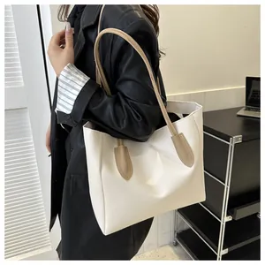 Large off-white tote bag with beige handles shown on model for shoulder style