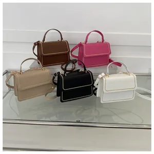 Detail view of colorful crocodile pattern crossbody bags with gold stud trim on glass stand