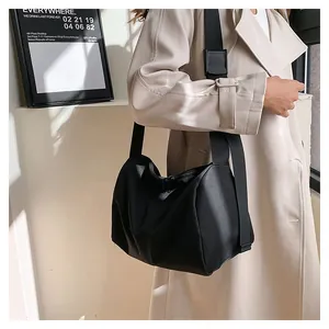 Detail of minimalist black nylon crossbody bag featuring adjustable wide shoulder strap