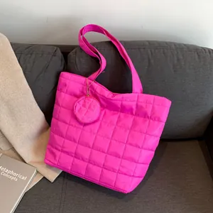 Leuchtend fuchsiafarbene Stepp-Tote-Bag mit rundem Münzetui auf grauem Sofa