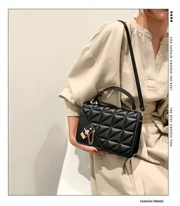 Détail du sac bandoulière noir matelassé avec fermoir doré et chaîne sur un mannequin