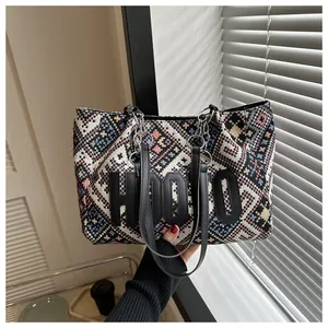 Detail of colorful geometric woven tote bag with HOOTO patch and black leather straps