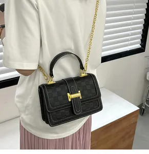 Close-up of black checkered embossed leather bag with contrast stitching and golden H buckle