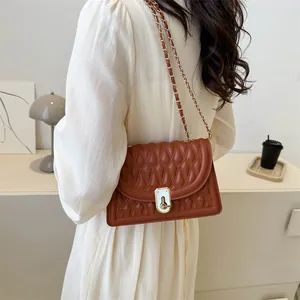 Brown quilted crossbody bag with gold chain strap and turn-lock closure on model