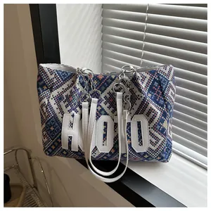 Detail of woven geometric pattern tote bag with HOO leather patch and metal chain strap