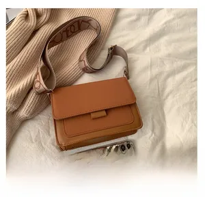Brown vintage flap bag with printed woven strap compared next to a mobile phone