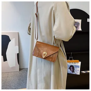 Detailed view of a brown vintage envelope bag with a golden heart-shaped metal lock