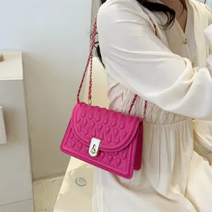 Magenta quilted crossbody bag with golden chain strap and lock shown on a model