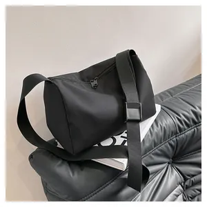Detail of black oxford fabric tote bag with adjustable shoulder strap on a quilted sofa