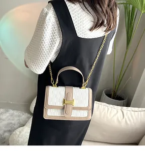 White checkered crossbody bag with gold hardware shown on model in cozy indoor setting