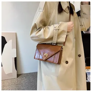Detailed shot of a brown vintage leather crossbody bag with a gold triangular metal clasp