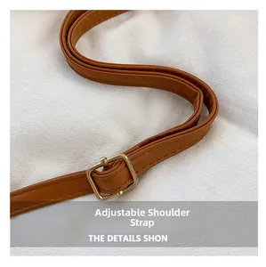 Détail de la bandoulière réglable en cuir marron avec boucle en métal doré et couture