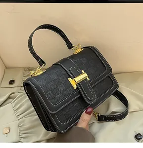 Close-up of black crossbody bag with checkerboard embossing and gold H-shaped clasp