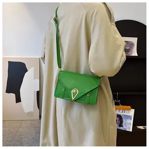 Detail view of bright green PU leather crossbody bag with a golden triangular buckle