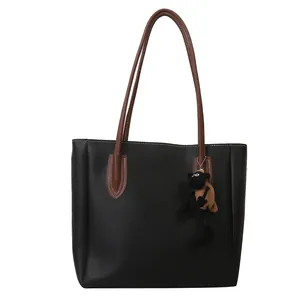 Black PU leather large capacity tote bag with brown straps and a cartoon plush charm