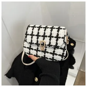 Detail of tweed checkered mini square bag with golden U-shaped lock and leather strap