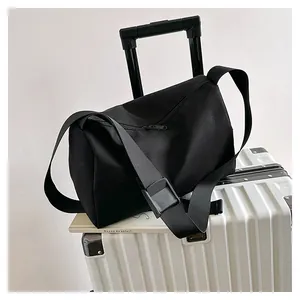 Detail of black nylon tote bag attached to white luggage handle for easy travel use