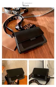 Close-up of black leather crossbody bag with a patterned wide textile strap on wooden desk