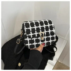 Detail of checkered tweed crossbody bag with golden U-shaped clasp and black leather trim