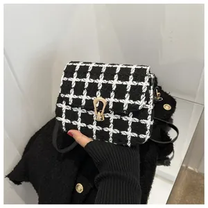 Close-up of black and white tweed plaid crossbody bag with gold horseshoe metal buckle