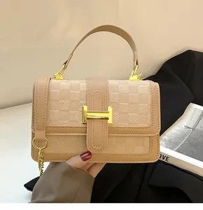 Close-up of beige checkerboard pattern leather with golden metal lock and chain strap