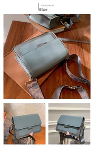 Detail of grey-blue crossbody bag featuring wide geometric patterned strap and gold hardware