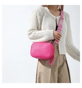Detail of pink lychee leather crossbody bag with ethnic style woven strap and gold zipper