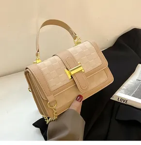 Close-up of beige embossed checkered pattern and gold H-shaped hardware on small square bag