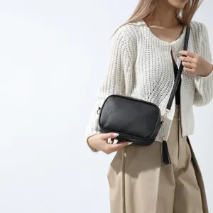Ethnic style black pebbled leather crossbody bag with tassel and gold hardware