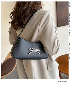 Detail of a black crescent shoulder bag with a silver rhinestone bow on the front