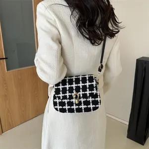 Minimalist black and white plaid crossbody bag with golden U-buckle worn by a model