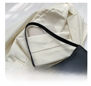 Close-up of black leather bag with silver rhinestone bow on white blazer