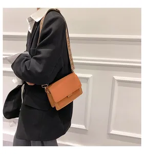 Detail view of orange crossbody bag with wide jacquard strap and accordion fold structure