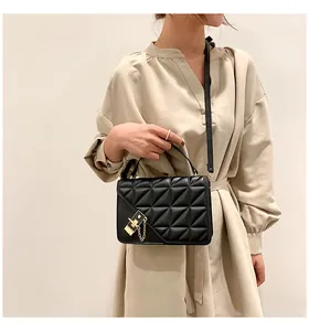 Détail du sac à bandoulière matelassé noir avec boucle dorée et chaîne élégante en métal