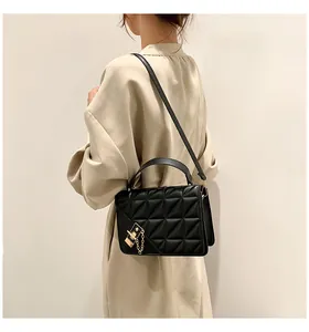 Gros plan du sac bandoulière noir matelassé avec détails dorés porté par un mannequin