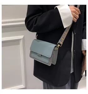 Detail of blue and gray patchwork crossbody bag with patterned wide strap and gold hardware