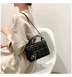 Détail d'un sac bandoulière matelassé noir avec fermoir doré porté par un mannequin
