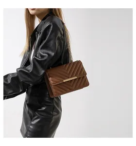 Detail of brown V-quilted faux leather bag with gold bar clasp and chain strap
