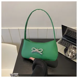 Close-up of vibrant green PU leather underarm bag featuring a crystal bow detail