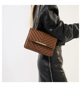 Detail of brown quilted shoulder bag with V-shaped stitching and golden metal trim