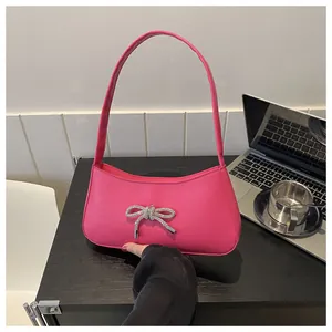 Macro view of magenta baguette bag with rhinestone bow and smooth leather texture