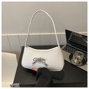 Detail showing white leather underarm bag with a sparkling silver rhinestone bow accessory