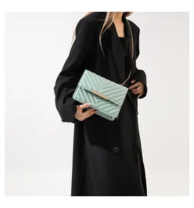 Detail of mint green chevron quilted small flap bag with gold chain strap on model