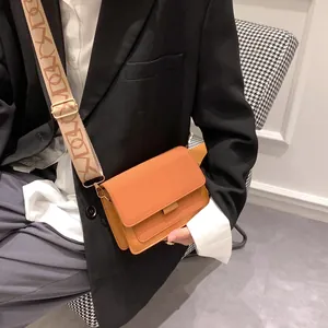 Retro orange crossbody square bag with a wide patterned woven strap on a female model