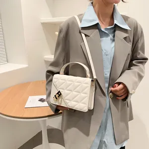 Sac à bandoulière matelassé blanc élégant avec chaîne dorée porté par un mannequin