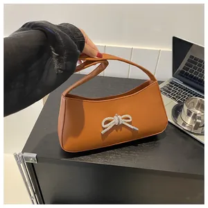 Detailed view of brown PU leather crescent shoulder bag with silver rhinestone bow accent