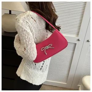 Detail of hot pink shoulder bag featuring a sparkling silver rhinestone bow decoration