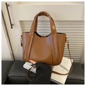 Close-up of brown textured leather bucket bag showing vertical stitching and gold hardware